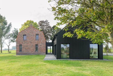 Moderne aanbouw woonboerderij bekleed met zwart geolied naaldhout