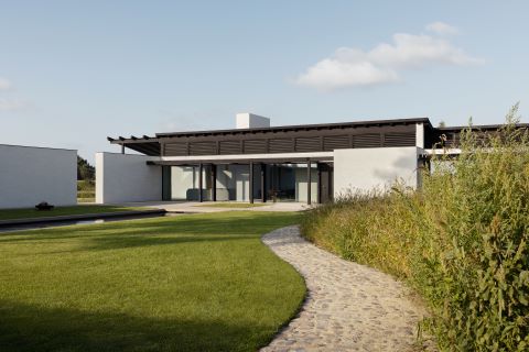 A modern villa with an exterior sun shade for a window in black wood