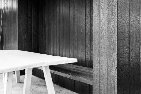 Strak contrast in zwart-wit: terrasoverkapping in gebrand hout met witte tafel