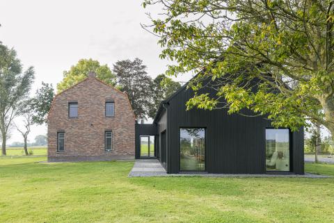 Holzanbau an ein Bauernhaus mit schwarzer Holzfassade in wechselnden Breiten