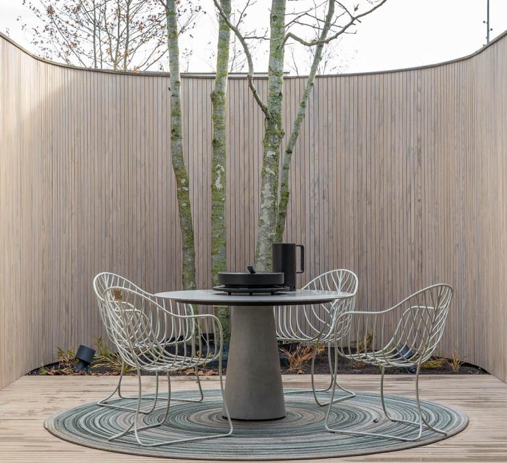 Dans un jardin urbain, une terrasse intime grâce à une clôture courbe