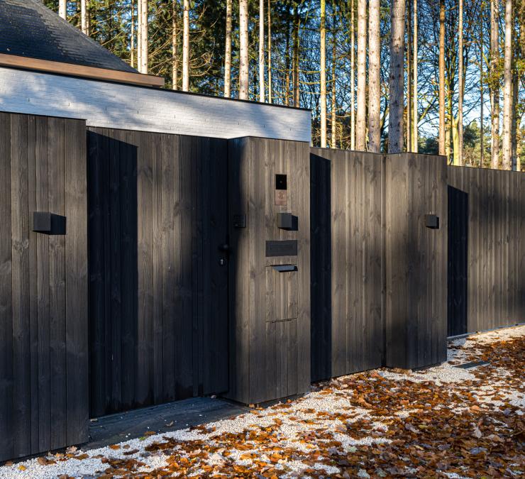 Portail coulissant en bois avec des poteaux revêtus et un portillon pour piétons